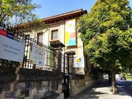 Entrada del Centre Cervantes Jove con señalización y entorno arbolado