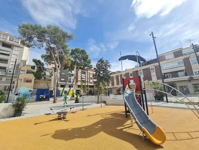 Área de juegos infantiles con toboganes y suelo de seguridad en la plaza