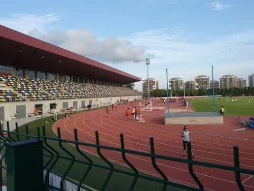 Gradas y pista de atletismo con espectadores y atletas