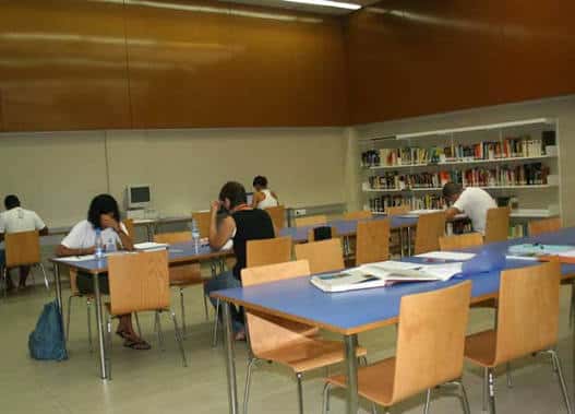 Sala de estudio de la biblioteca con mesas y estanterías