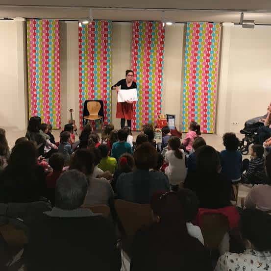 Evento de lectura en la biblioteca con público y decoración colorida