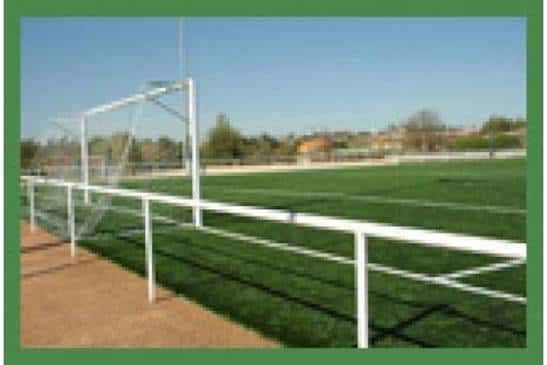 Vista del campo de fútbol con portería y valla perimetral bajo cielo despejado