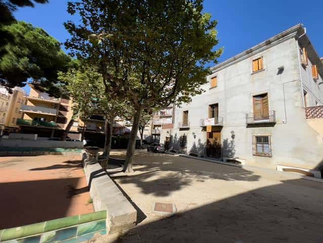 Vista lateral de Les Esmandies con árboles y plaza adyacente bajo cielo despejado