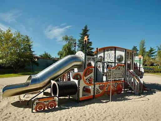 Juego infantil con tobogán metálico y estructura de tren en Parque Primero de Mayo