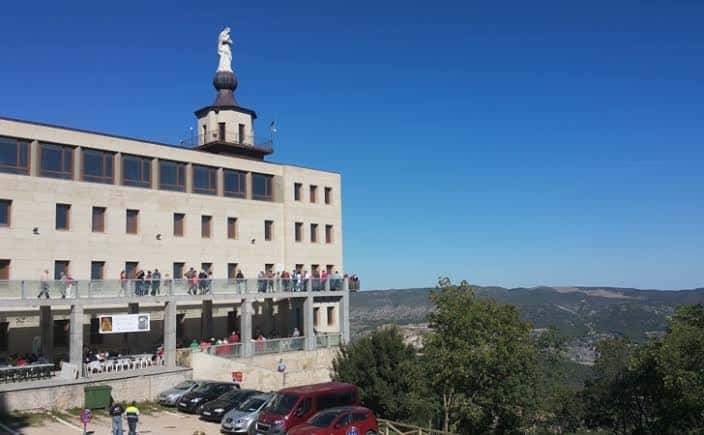 Vista exterior del Centro de Visitantes de la Font Roja con el Santuario al fondo y visitantes en la terraza