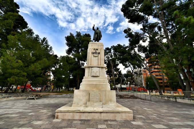 Monumento a Emilio Castelar en el centro de la plaza con árboles y cielo nublado