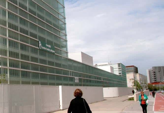 Fachada lateral del edificio con cartel de 'Centro de Servicios Sociales Mayores' y peatones en primer plano