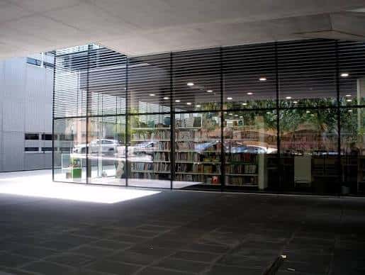 Interior de la biblioteca con estanterías y grandes ventanales de cristal