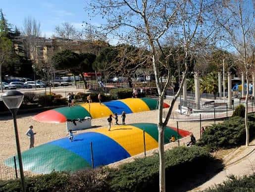 Vista panorámica del parque con estructuras de juegos infantiles coloridas y áreas verdes