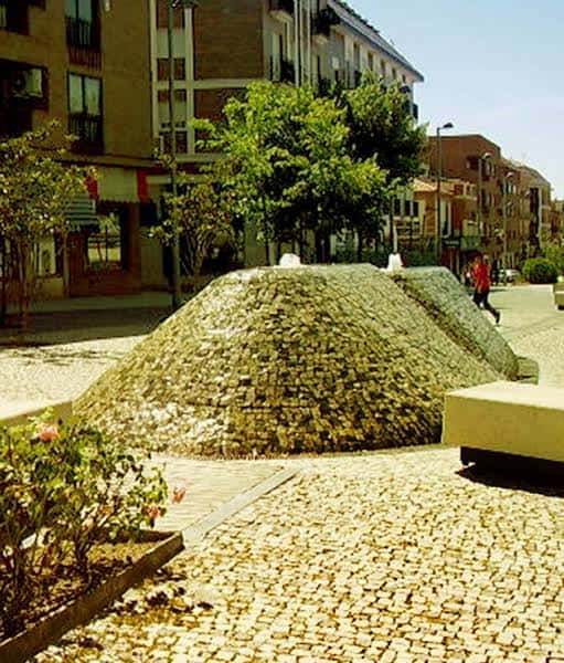 Plaza con fuente de piedra y adoquinado en la Calle Real
