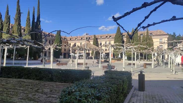 Plaza arbolada con pérgolas y edificios de fondo en Las Rozas