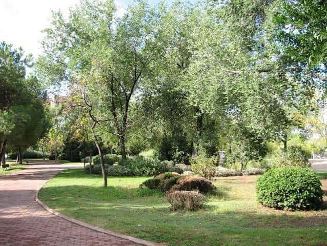 Área ajardinada del parque con caminos de ladrillo y arbustos bien cuidados