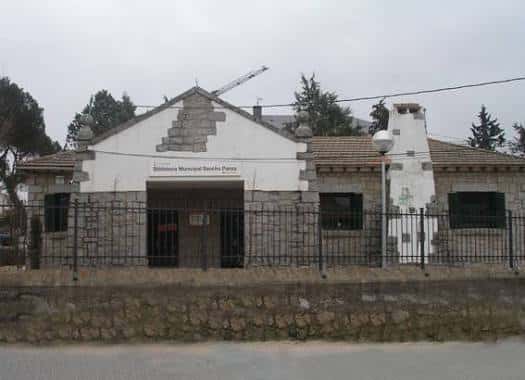 Vista exterior completa de la Biblioteca Municipal Sancho Panza con valla y entorno arbolado