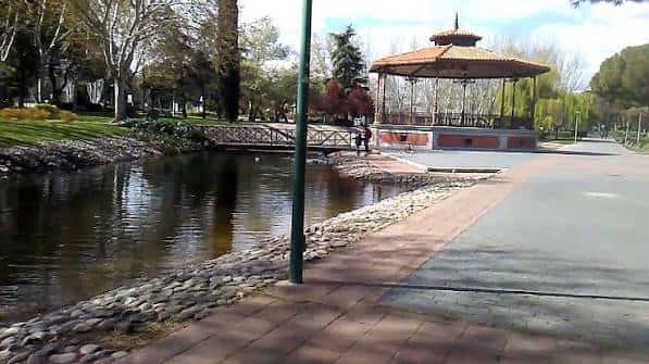 Vista del parque con un lago, puente y kiosco en un día soleado