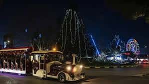 Escenario nocturno del parque con tren turístico y atracciones iluminadas