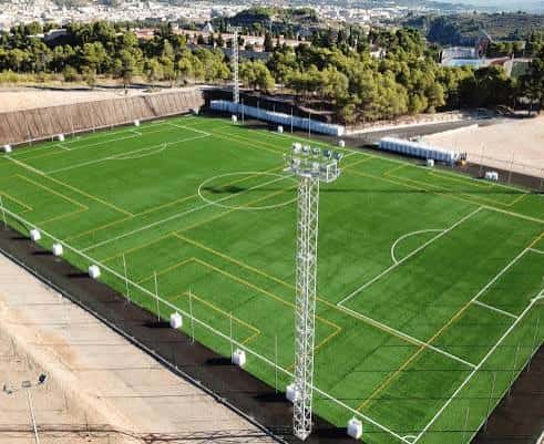 Vista aérea del campo de fútbol con césped artificial y torres de iluminación