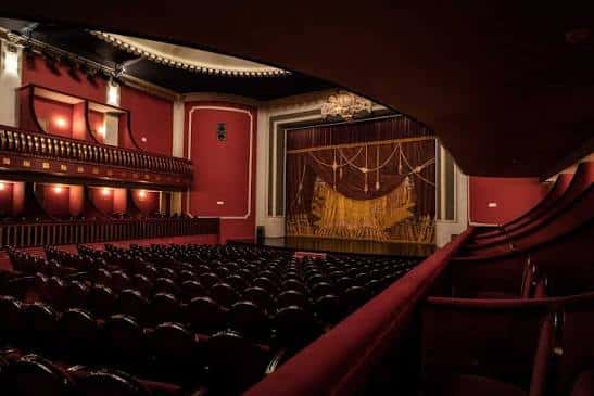 Vista del escenario del Teatro Castelar con el telón dorado y las butacas rojas