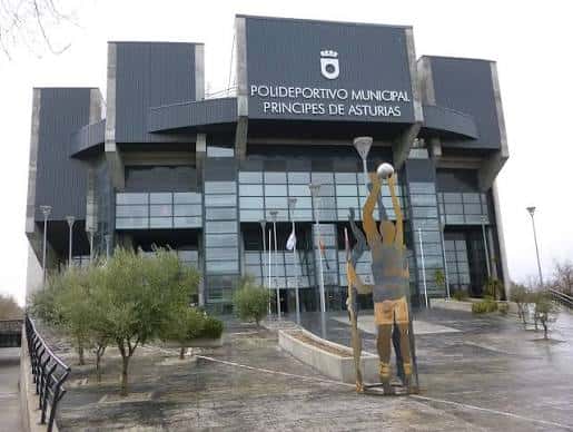 Vista frontal del Polideportivo Municipal Príncipes de Asturias con escultura deportiva en primer plano