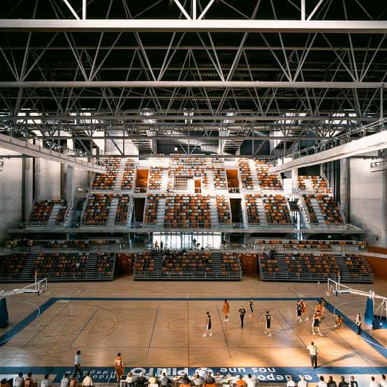 Interior del pabellón con gradas y cancha de baloncesto en uso