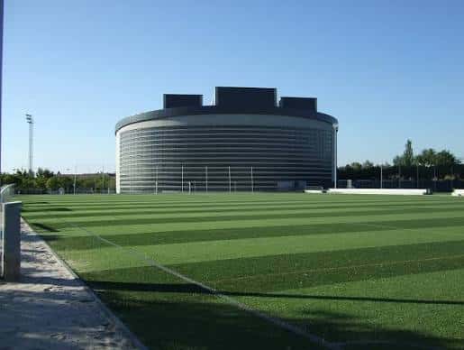 Exterior del polideportivo visto desde el campo de fútbol con césped artificial