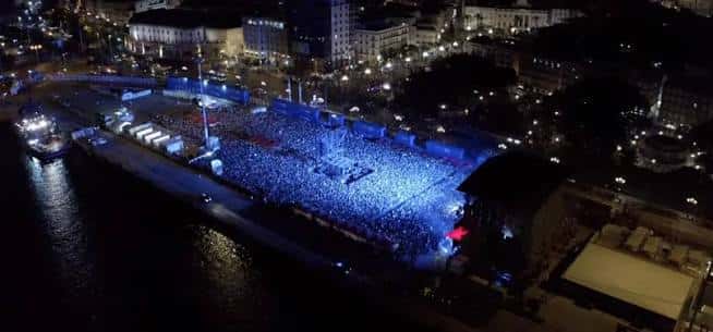 Vista aérea nocturna del Muelle Reina Victoria con un gran evento al aire libre