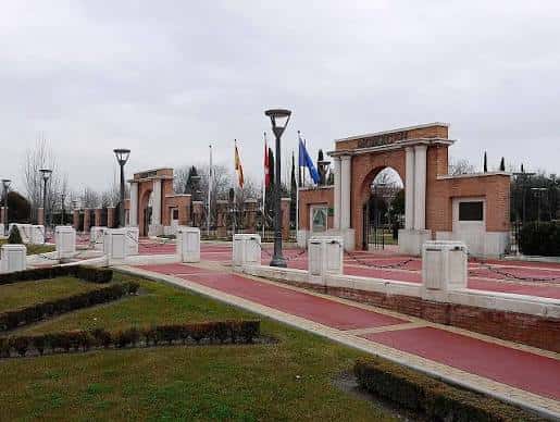 Entrada monumental con arcos de ladrillo y banderas en el parque