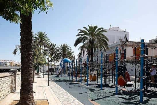 Paseo peatonal con zona de juegos y palmeras frente al Anfiteatro de la Alameda del Río