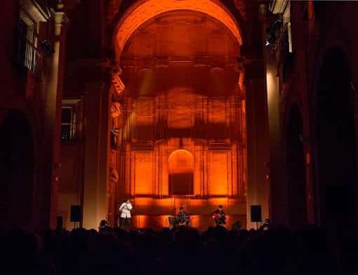 Interior del Teatro Municipal con escenario iluminado en tonos cálidos y público en primer plano