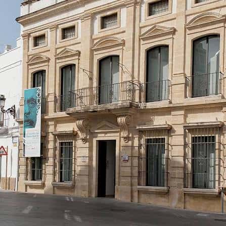 Vista lateral del museo con cartel de exposición y detalles arquitectónicos