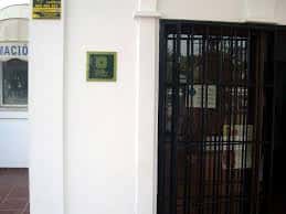Detalle de la entrada con placa conmemorativa y reja metálica en la Oficina de Turismo de Mijas