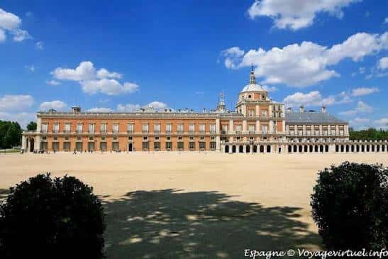 Plaza de Parejas en Aranjuez bajo cielo azul, mostrando la fachada principal del Palacio Real