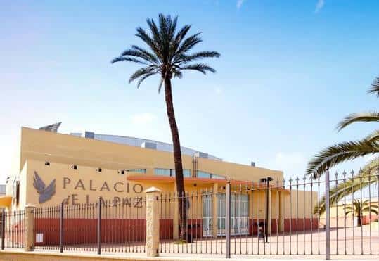 Fachada principal del Palacio de la Paz con letrero y palmera alta al frente