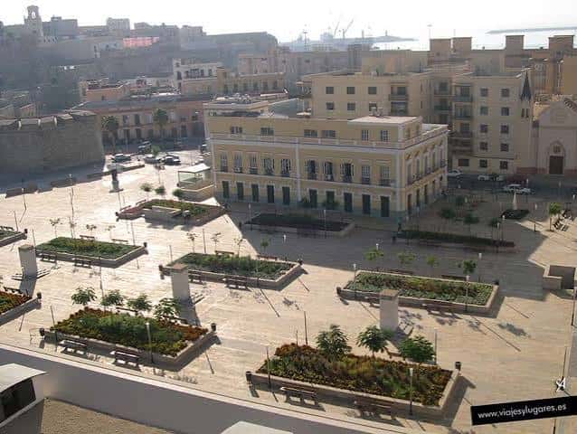 Plaza de las Culturas con el edificio amarillo y murallas históricas al fondo