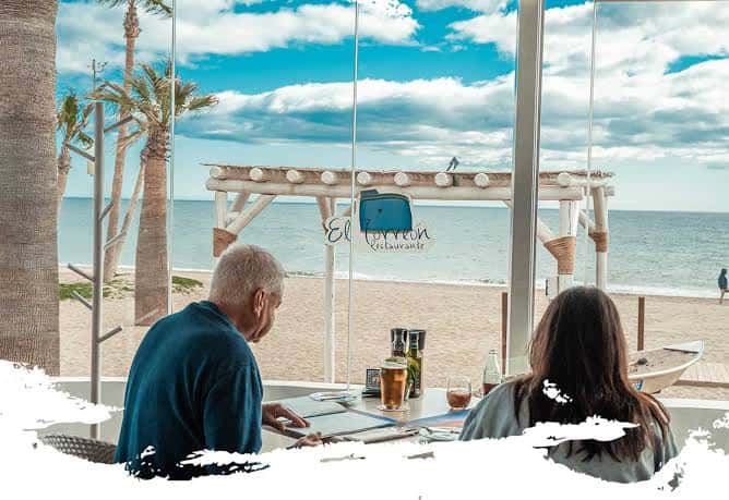 Interior del restaurante con vista al mar, mostrando la terraza y el ambiente acogedor para eventos