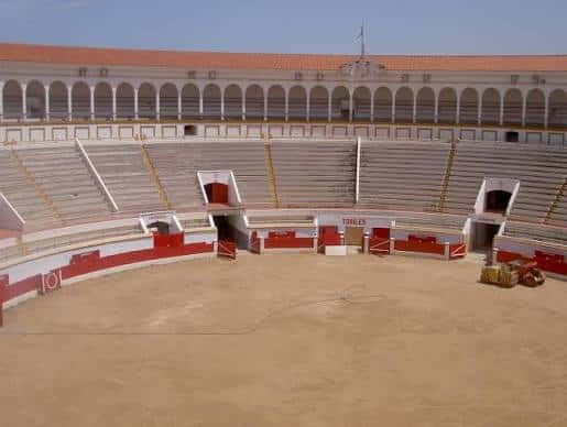 Vista panorámica del interior de la plaza de toros con gradas vacías y arena