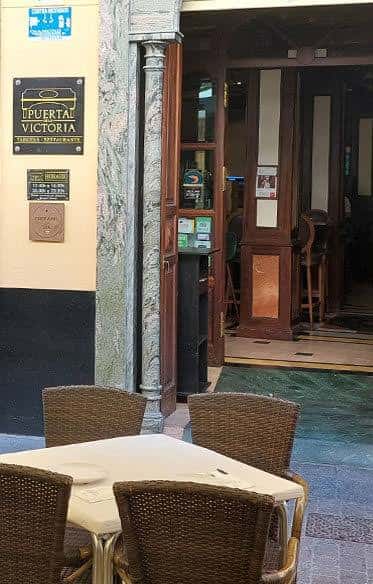 Entrada del Bar Puerta de la Victoria con mesas exteriores