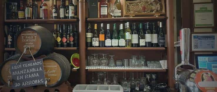 Estantería de vinos y barriles en el interior del bar
