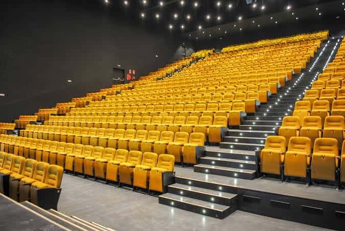 Interior del auditorio con butacas amarillas y escaleras iluminadas