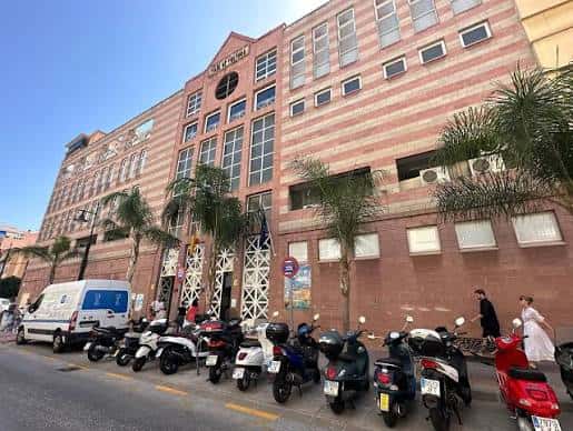 Vista general del edificio de la Casa de la Cultura con palmeras y vehículos en la calle