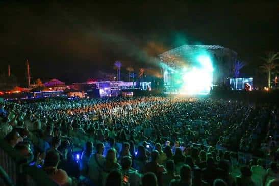 Vista nocturna del concierto con multitud y escenario iluminado