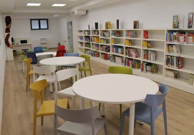Interior de la Biblioteca Infantil Tirisiti con estanterías blancas y mesas redondas