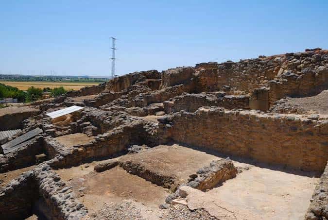Vista general de las excavaciones arqueológicas con estructuras de piedra y cielo despejado