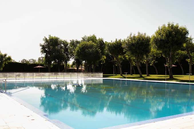 Piscina exterior del Club de Tenis Oromana con árboles al fondo
