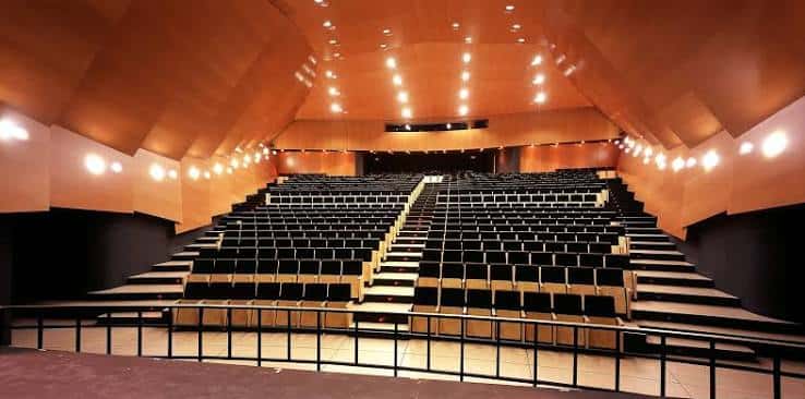 Interior del auditorio con butacas negras y techo acústico de madera
