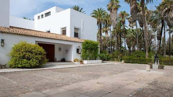 Fachada principal de Villa Astrida con palmeras y entrada pavimentada
