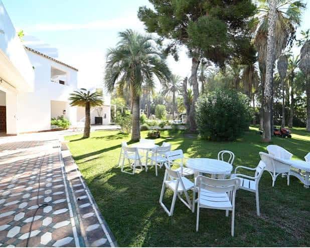 Jardín exterior de Villa Astrida con mesas y sillas blancas para eventos
