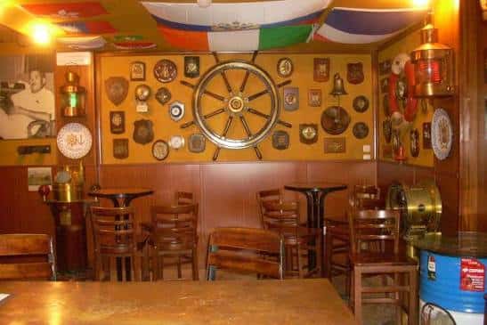 Interior del Bar Neno con decoración náutica, timón central y banderas colgantes