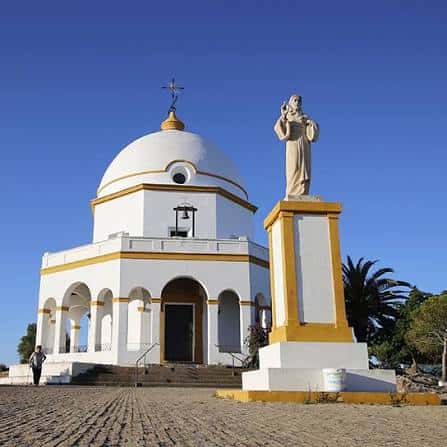 Vista frontal de la Ermita de Santa Ana con su estatua bajo un cielo despejado