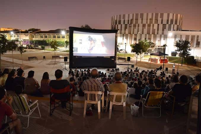 Cine de verano en el Anfiteatro Felipe Bellver con público sentado y pantalla grande al atardecer