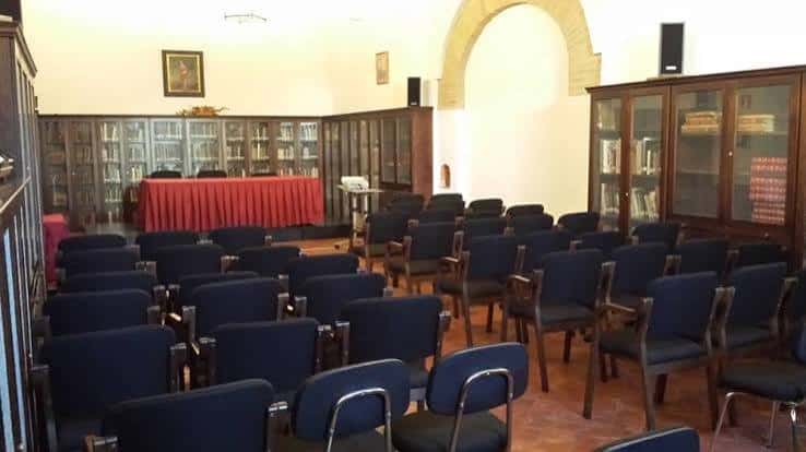 Sala de actos con butacas y mesa presidencial en la biblioteca